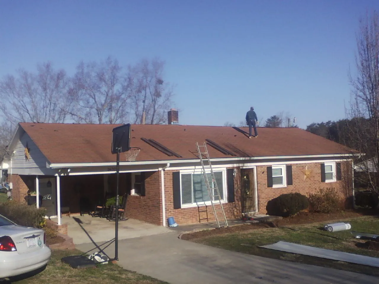 Roofer stripping a shingle roof on a brick ranch before metal panels in Cleves
