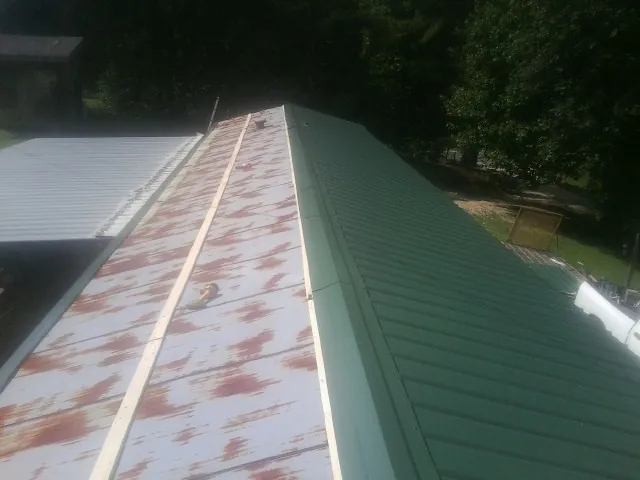 Old rusted panels beside newly installed green metal roofing — Wind Damage Roof Repair by Roofing Brothers in Cleves
