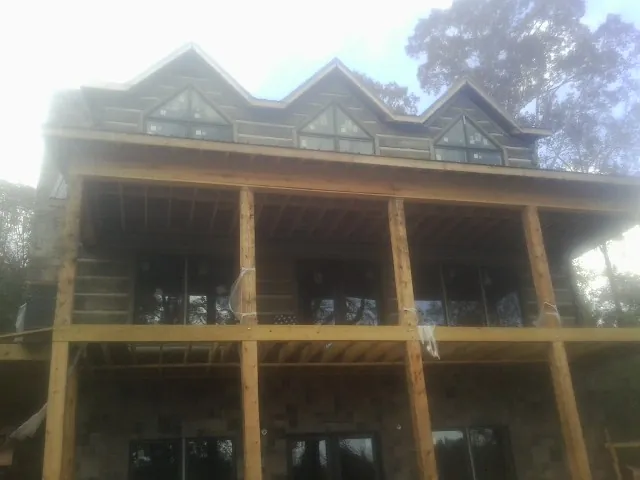 Dormers and porch framing on a large log home under construction — Roof Coating work by our crew in Cleves