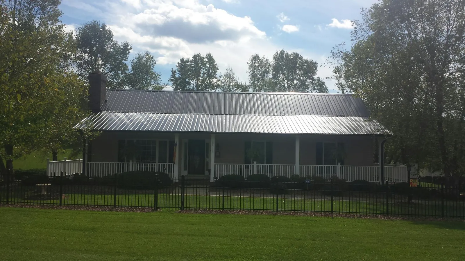 Gray metal roof on a brick ranch with a full width front porch — Gutter Guard Installation work by our crew in Cleves