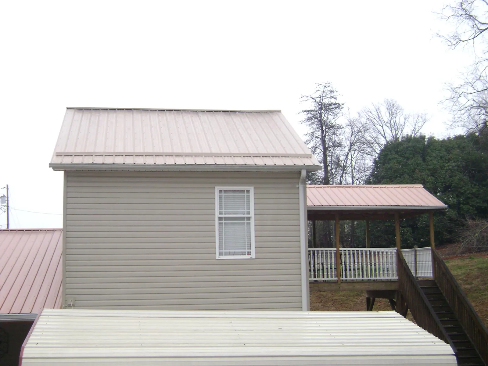 Tan metal roofs on a two story addition and attached porch, from a Roof Replacement job in Cleves